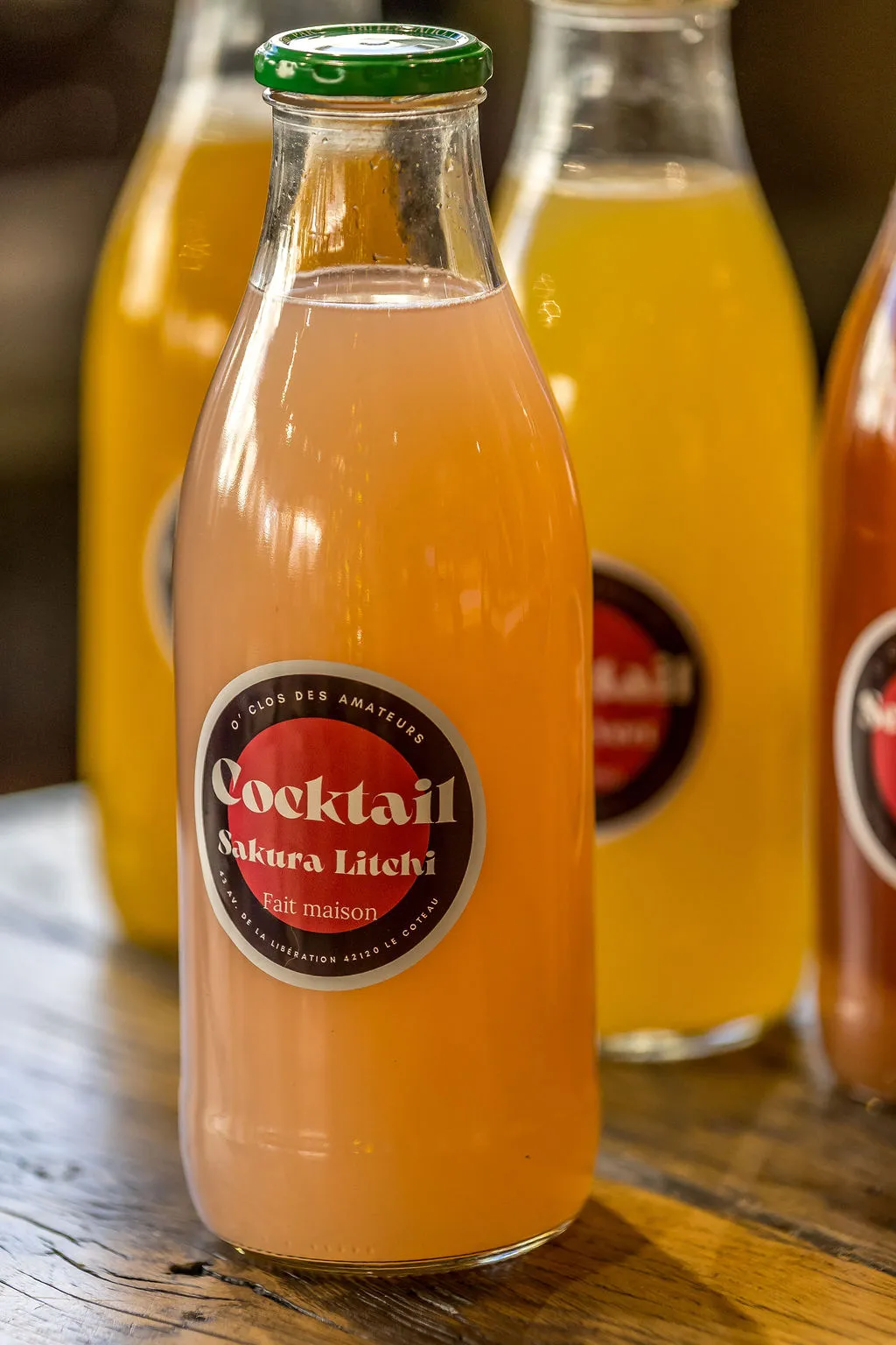 Cocktail signature O'Clos garni d'une fleur de sakura, présenté au comptoir