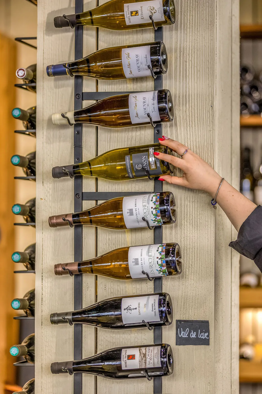 Main choisissant une bouteille devant un casier Val de Loire