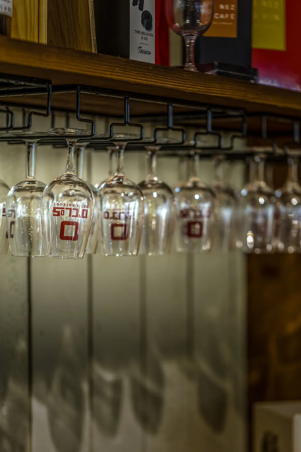 Verres siglés O'Clos des Amateurs suspendus au-dessus du bar de la cave
